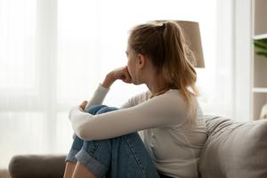 A young woman sits looking out the window contemplating an abortion. A young woman sits looking out the window contemplating an abortion.