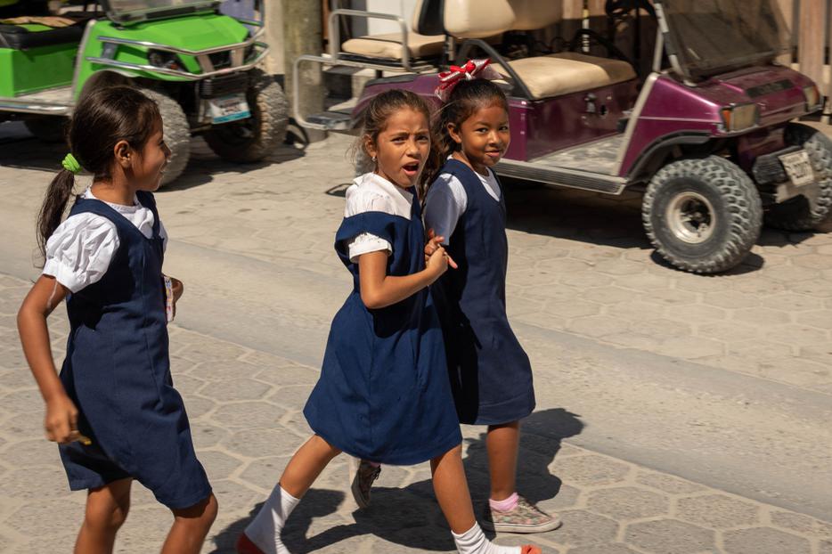 Three local Belizean girls crossing the street during lunch break in Catholic school San Pedro, Belize on November, 15, 2019. Three local Belizean girls crossing the street during lunch break in Catholic school San Pedro, Belize on November, 15, 2019.