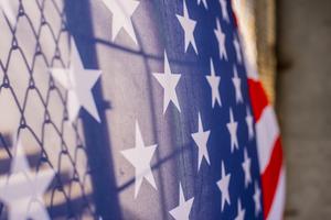 An American flag is shown draped over a border fence. An American flag is shown draped over a border fence.