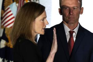Judge Amy Coney Barrett is sworn in as a U.S. Supreme Court associate justice during a ceremony on the South Lawn of the White House Oct. 26. Her husband, Jesse, looks on. Judge Amy Coney Barrett is sworn in as a U.S. Supreme Court associate justice during a ceremony on the South Lawn of the White House Oct. 26. Her husband, Jesse, looks on.