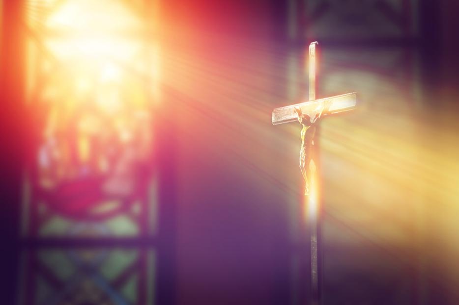 Rays of light from a stained glass window shine down on a crucifix inside a Catholic church. Rays of light from a stained glass window shine down on a crucifix inside a Catholic church.