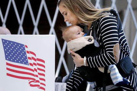 Voter Izzi Buckles holds her son, Rowan, as she marks her ballot in a polling place at Roosevelt High School on Nov. 3 in Des Moines, Iowa. The election results are still not settled, and Catholics are urged to keep a Christ-focused perspective in these challenging times.