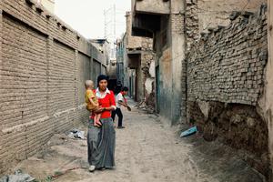 Young Uyghur mother with child walking in the outskirts of Kashgar, China.