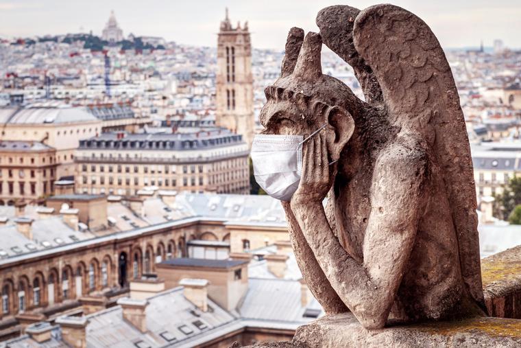 Gargoyle sits atop Notre Dame in Paris wearing a face mask. Gargoyle sits atop Notre Dame in Paris wearing a face mask.
