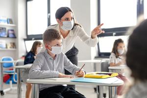 A teacher helps a student inside the classroom amid the coronavirus pandemic.