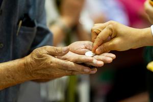 A priest offers a parishioner the Eucharist by hand. A priest offers a parishioner the Eucharist by hand.