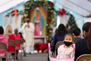 A girl wears a face covering as Father Rafael Saiz holds Christmas Mass outdoors at St. Mary's Catholic Church on Dec. 25, 2020, in Los Angeles. A girl wears a face covering as Father Rafael Saiz holds Christmas Mass outdoors at St. Mary's Catholic Church on Dec. 25, 2020, in Los Angeles.