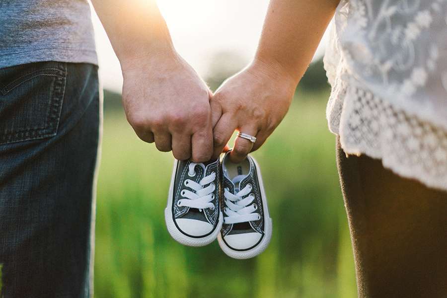 Adoptive parents hold infant shoes in anticipation of receiving their little one. Adoptive parents hold infant shoes in anticipation of receiving their little one.