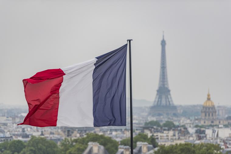 French flag waves above Paris with the Eiffel Tower in the background. French flag waves above Paris with the Eiffel Tower in the background.