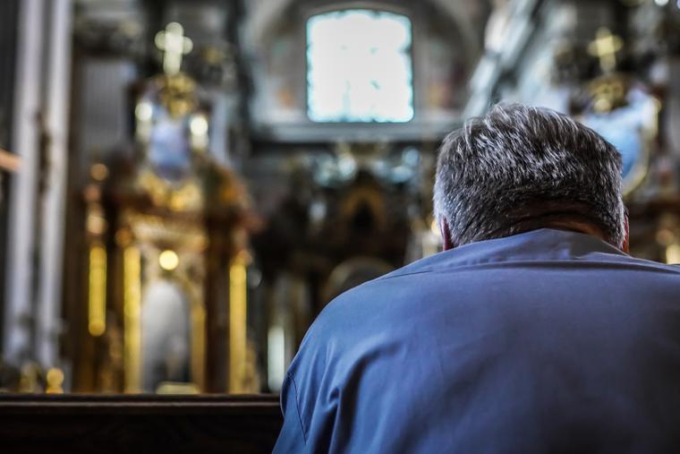 A man sits alone inside a Catholic church praying. A man sits alone inside a Catholic church praying.