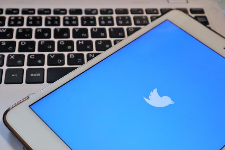 A smartphone showing the Twitter logo rests on a laptop. A smartphone showing the Twitter logo rests on a laptop.