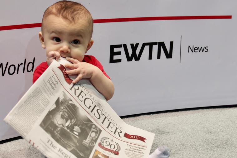 A young baby consuming every page of the National Catholic Register newspaper. A young baby consuming every page of the National Catholic Register newspaper.