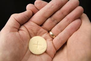 A man receives Communion in the hand. A man receives Communion in the hand.