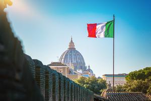 View of Saint Peter Basilica with an Italian flag waving in the wind. View of Saint Peter Basilica with an Italian flag waving in the wind.