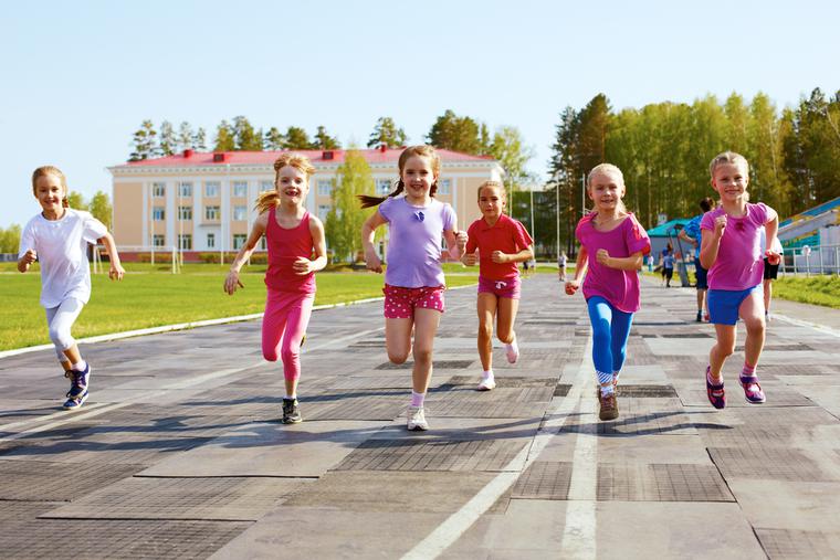 Young girls run outside on the track. Young girls run outside on the track.