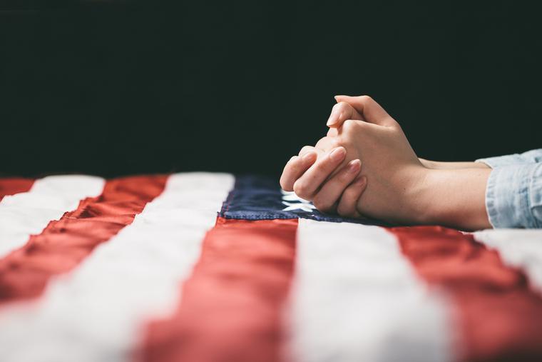 A woman prays over the American flag. A woman prays over the American flag.