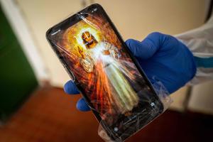 Father Martin Miskuf shows his mobile phone wrapped in plastic to a COVID patient hospitalized at University Hospital J.A. Reiman in Presov, Slovakia on February 18, 2021. In a hospital with broken windows and peeling paint in a poor part of Slovakia, dozens of Catholic priests have volunteered since January to provide spiritual assistance in particularly busy Covid wards, helping overworked medical staff battling the world's second highest Covid mortality rate. Father Martin Miskuf shows his mobile phone wrapped in plastic to a COVID patient hospitalized at University Hospital J.A. Reiman in Presov, Slovakia on February 18, 2021. In a hospital with broken windows and peeling paint in a poor part of Slovakia, dozens of Catholic priests have volunteered since January to provide spiritual assistance in particularly busy Covid wards, helping overworked medical staff battling the world's second highest Covid mortality rate.
