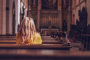 A woman sits alone inside a parish praying. A woman sits alone inside a parish praying.