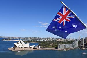 The National flag of Australia flies above the Sydney Harbor and the Opera house in Australia. The National flag of Australia flies above the Sydney Harbor and the Opera house in Australia.