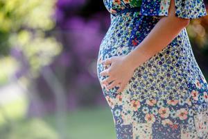 A pregnant woman stands alone in the park. A pregnant woman stands alone in the park.