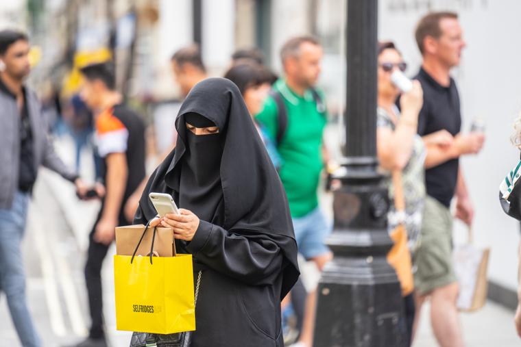 A woman wearing a niqab, using mobile phone while shopping. A woman wearing a niqab, using mobile phone while shopping.