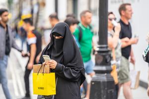 A woman wearing a niqab, using mobile phone while shopping. A woman wearing a niqab, using mobile phone while shopping.