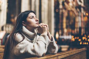 A young female parishioners sits praying at a Catholic church. A young female parishioners sits praying at a Catholic church.