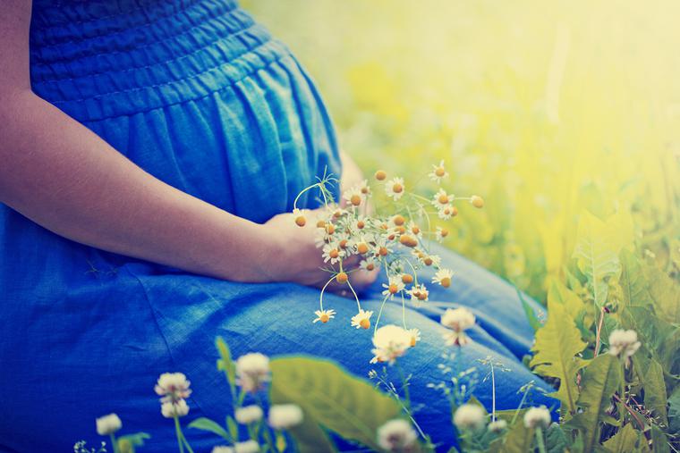 A pregnant woman kneels in a garden. A pregnant woman kneels in a garden.