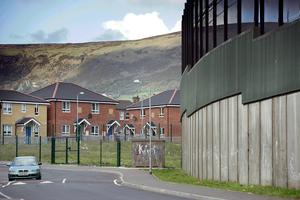 The "peace line," a 25-foot high brick, steel and wire structure separating the city's nationalist and unionist communities, can be seen beside new homes in west Belfast, Northern Ireland, on April 29, 2008.