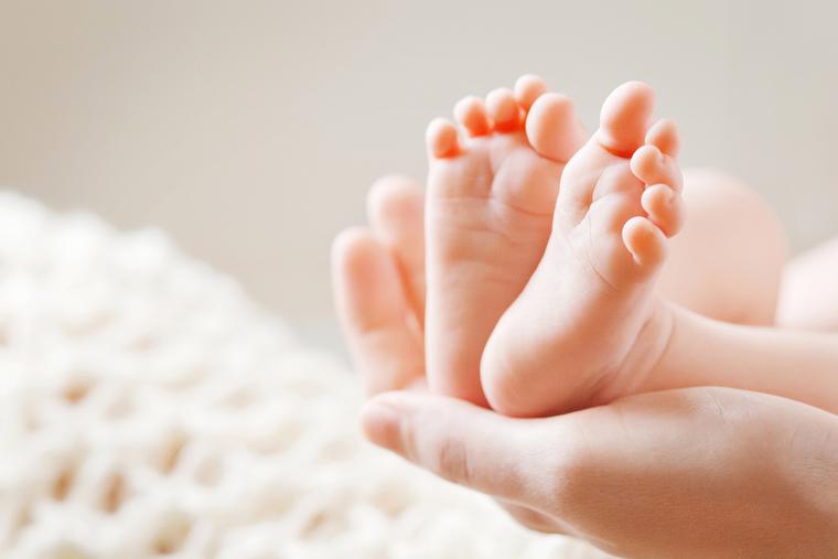 Mother holds baby's feet in the palm of her hands. Mother holds baby's feet in the palm of her hands.