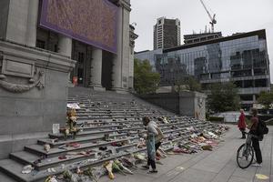 People place flowers and children's shoes at a memorial in Vancouver on May 30, 2021 People place flowers and children's shoes at a memorial in Vancouver on May 30, 2021