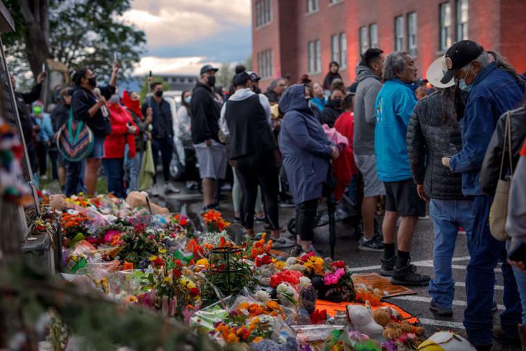 People gather outside the former Kamloops Indian Residential School as they welcome a group of runners from the Syilx Okanagan Nation taking part in The Spirit of Syilx Unity Run, following the discovery of the remains of 215 children buried near the facility, in Kamloops, British Columbia, Canada, on June 5, 2021. People gather outside the former Kamloops Indian Residential School as they welcome a group of runners from the Syilx Okanagan Nation taking part in The Spirit of Syilx Unity Run, following the discovery of the remains of 215 children buried near the facility, in Kamloops, British Columbia, Canada, on June 5, 2021.