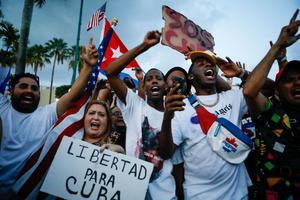 A woman holds a placard reading "Freedom for Cuba" as others demonstrate holding Cuban and US National flags during a protest against the Cuban government in Miami on July 11, 2021. A woman holds a placard reading "Freedom for Cuba" as others demonstrate holding Cuban and US National flags during a protest against the Cuban government in Miami on July 11, 2021.