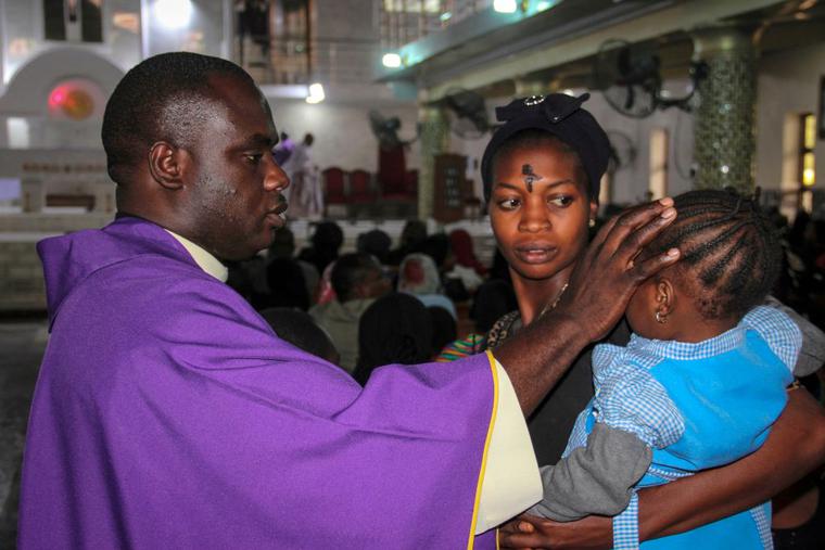 A priest signs the forehead of a child as catholics take part in the Ash Wednesday celebration at the St. Patrick cathedral in Maiduguri on February 26, 2020. A priest signs the forehead of a child as catholics take part in the Ash Wednesday celebration at the St. Patrick cathedral in Maiduguri on February 26, 2020.