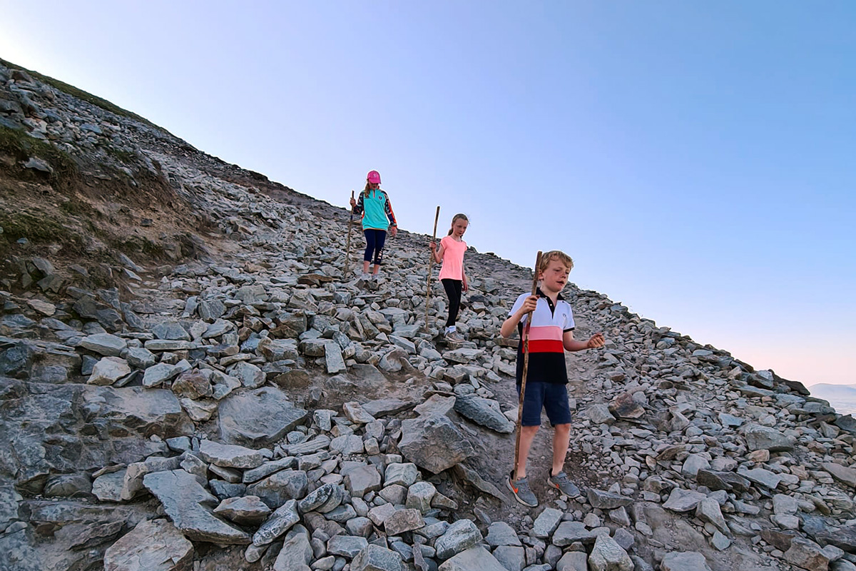 Pilgrims descend Croagh Patrick with a wooden staff to help navigate rough ground.