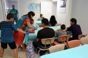 A volunteer at a Catholic Charities Humanitarian Respite Center gives a Central American refugee girl a bowl of soup. A volunteer at a Catholic Charities Humanitarian Respite Center gives a Central American refugee girl a bowl of soup.