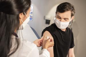 A health care provider places a bandage on the injection site of a patient, who just received the COVID vaccine. A health care provider places a bandage on the injection site of a patient, who just received the COVID vaccine.