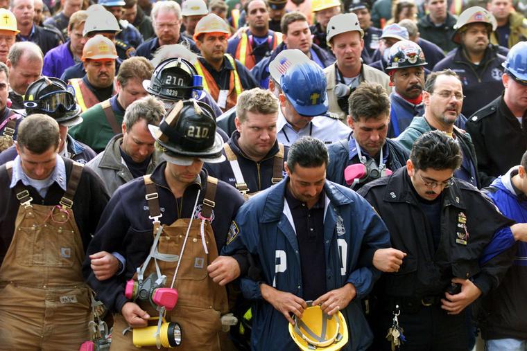 Firemen, police officers, and workers lock arms while observing a moment of silence during a short interfaith memorial service held at the World Trade Center disaster site 11 October, 2001 in New York. Firemen, police officers, and workers lock arms while observing a moment of silence during a short interfaith memorial service held at the World Trade Center disaster site 11 October, 2001 in New York.