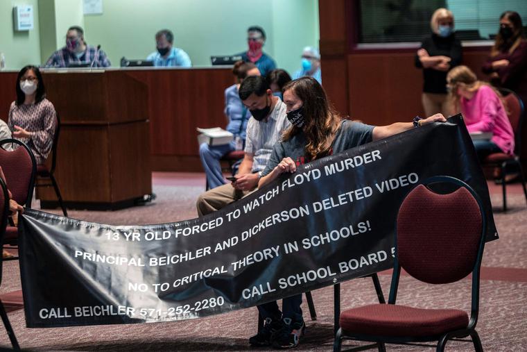 A woman holds up her sign against Critical Race Theory (CRT) being taught during a Loudoun County Public Schools (LCPS) board meeting in Ashburn, Virginia, on Oct. 12. The Loudoun county school board has clashed with parents over transgender issues, the teaching of CRT and COVID-19 mandates. Recently tensions between parents and the school board increased after parents say a young male wearing a dress sexually assaulted a girl in a school restroom. A woman holds up her sign against Critical Race Theory (CRT) being taught during a Loudoun County Public Schools (LCPS) board meeting in Ashburn, Virginia, on Oct. 12. The Loudoun county school board has clashed with parents over transgender issues, the teaching of CRT and COVID-19 mandates. Recently tensions between parents and the school board increased after parents say a young male wearing a dress sexually assaulted a girl in a school restroom.