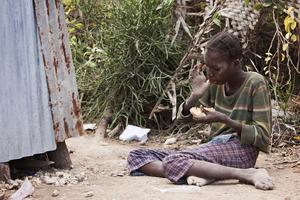 Young Haitian girl sitting on the ground eating peanut butter bread given to her by missionaries. Young Haitian girl sitting on the ground eating peanut butter bread given to her by missionaries.