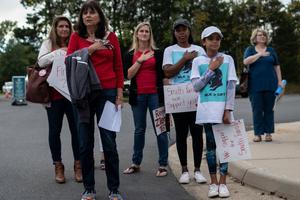 Protesters and activists stand at attention as the national anthem is sung to open a Loudoun County Public Schools board meeting in Ashburn, Virginia, on Oct. 12. Loudoun County school-board meetings have become tense recently, with parents clashing with board members over issues such as the teaching of critical race theory and the response to in-school sexual-assault allegations. Directives from the U.S. attorney general have also angered parents of late. Protesters and activists stand at attention as the national anthem is sung to open a Loudoun County Public Schools board meeting in Ashburn, Virginia, on Oct. 12. Loudoun County school-board meetings have become tense recently, with parents clashing with board members over issues such as the teaching of critical race theory and the response to in-school sexual-assault allegations. Directives from the U.S. attorney general have also angered parents of late.