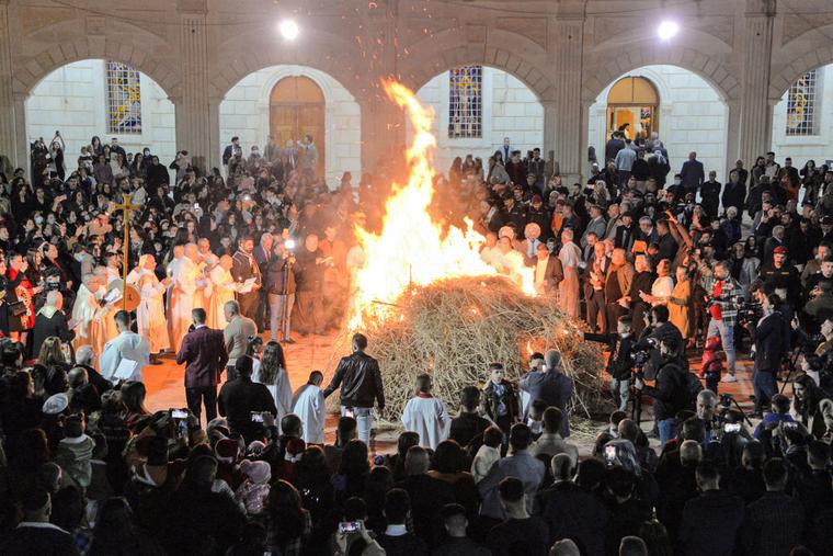 Christian worshippers gather around a bonfire outside the Syriac Catholic Church of the Immaculate Conception (Al-Tahira-l-Kubra), in Iraq's predominantly Christian town of Qaraqosh (Baghdeda), in Nineveh province, some 30 kilometres from Mosul, during the Christmas eve service on December 24, 2021. Christian worshippers gather around a bonfire outside the Syriac Catholic Church of the Immaculate Conception (Al-Tahira-l-Kubra), in Iraq's predominantly Christian town of Qaraqosh (Baghdeda), in Nineveh province, some 30 kilometres from Mosul, during the Christmas eve service on December 24, 2021.