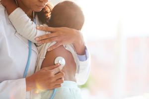 A doctor holding baby and listening to him with a stethoscope A doctor holding baby and listening to him with a stethoscope