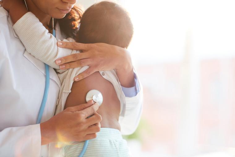 A doctor holding baby and listening to him with a stethoscope A doctor holding baby and listening to him with a stethoscope