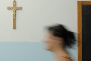 A crucifix is seen on the wall of a Catholic school classroom. A crucifix is seen on the wall of a Catholic school classroom.
