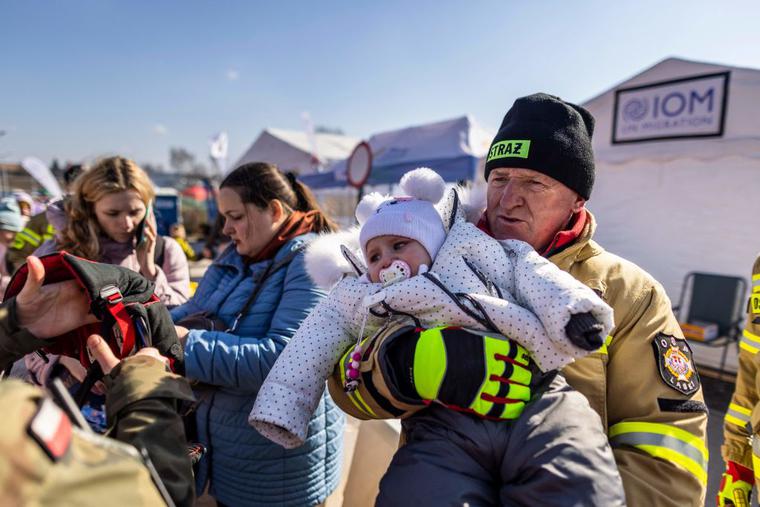 A polish fireman holds a baby at the Medyka border crossing on March 17, 2022. More than three million Ukrainians have fled across the border, mostly women and children, according to the UN. A polish fireman holds a baby at the Medyka border crossing on March 17, 2022. More than three million Ukrainians have fled across the border, mostly women and children, according to the UN.