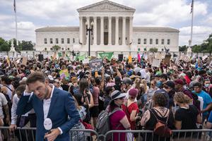 A journalist reports near a crowd of pro-abortion activists in front of the U.S. Supreme Court after the Court announced a ruling in the Dobbs v. Jackson Women's Health Organization case on Friday in Washington, DC. A journalist reports near a crowd of pro-abortion activists in front of the U.S. Supreme Court after the Court announced a ruling in the Dobbs v. Jackson Women's Health Organization case on Friday in Washington, DC.