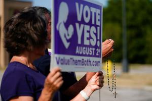 Catholic deacon John Stanley and his wife Connie Stanley pray and wave at cars while holding signs in support of the Vote Yes to a Constitutional Amendment on Abortion along 135th Street on August 01, 2022 in Olathe, Kansas. Catholic deacon John Stanley and his wife Connie Stanley pray and wave at cars while holding signs in support of the Vote Yes to a Constitutional Amendment on Abortion along 135th Street on August 01, 2022 in Olathe, Kansas.