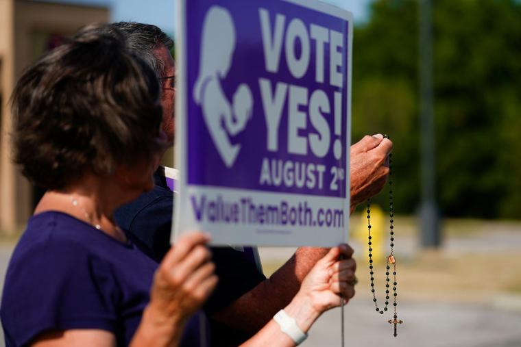 Catholic deacon John Stanley and his wife Connie Stanley pray and wave at cars while holding signs in support of the Vote Yes to a Constitutional Amendment on Abortion along 135th Street on August 01, 2022 in Olathe, Kansas. Catholic deacon John Stanley and his wife Connie Stanley pray and wave at cars while holding signs in support of the Vote Yes to a Constitutional Amendment on Abortion along 135th Street on August 01, 2022 in Olathe, Kansas.