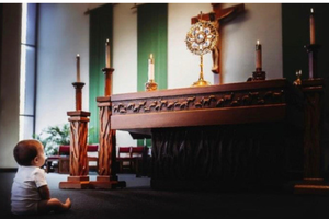 A toddler stares intently at the Blessed Sacrament. A toddler stares intently at the Blessed Sacrament.